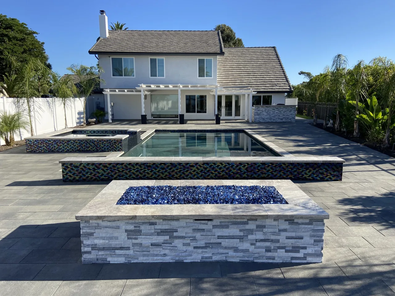 A house with a backyard swimming pool, pool lounge, and firepit