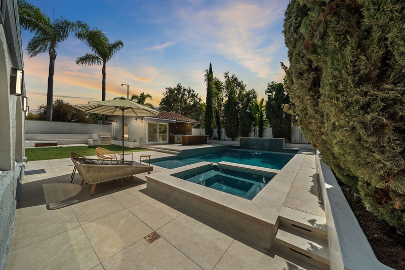 Backyard pool and spa with lounge area at sunset