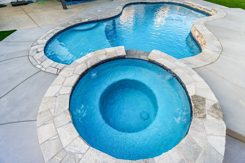 Stone-lined spa connected to custom backyard pool