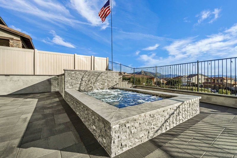 Modern raised spa with waterfall by California Custom Pools