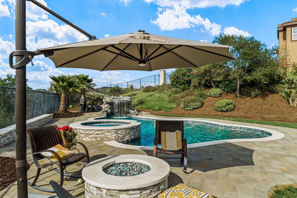 Backyard pool patio with spa, waterfall, and shade umbrella
