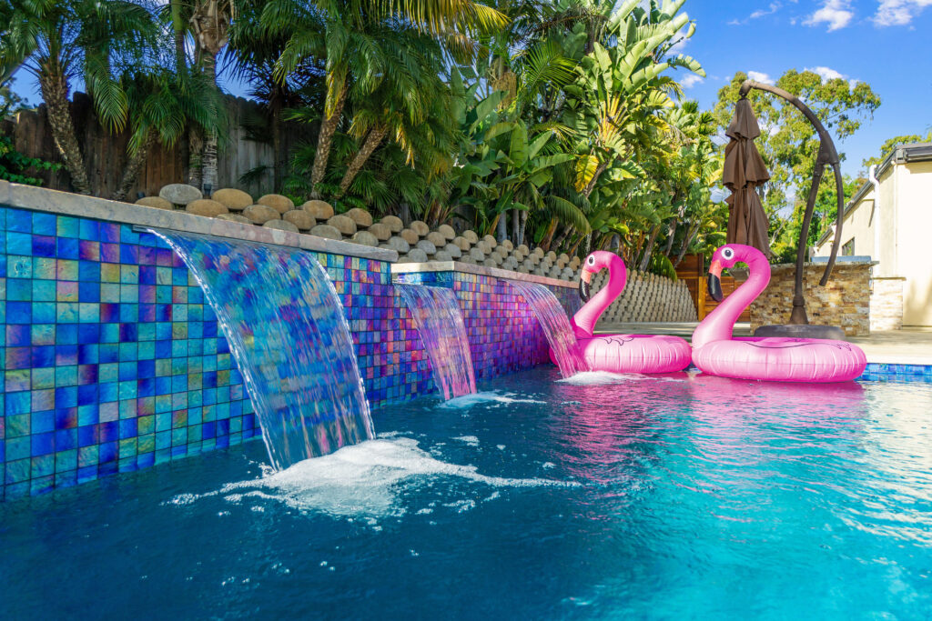 Pool waterfalls with pink flamingo floats and blue tile