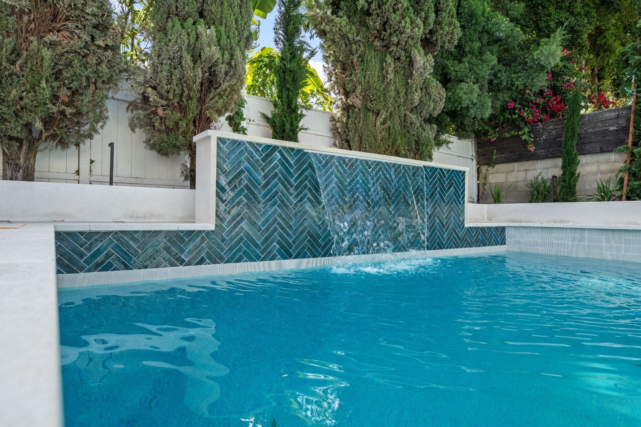 Pool with herringbone tile wall and waterfall feature