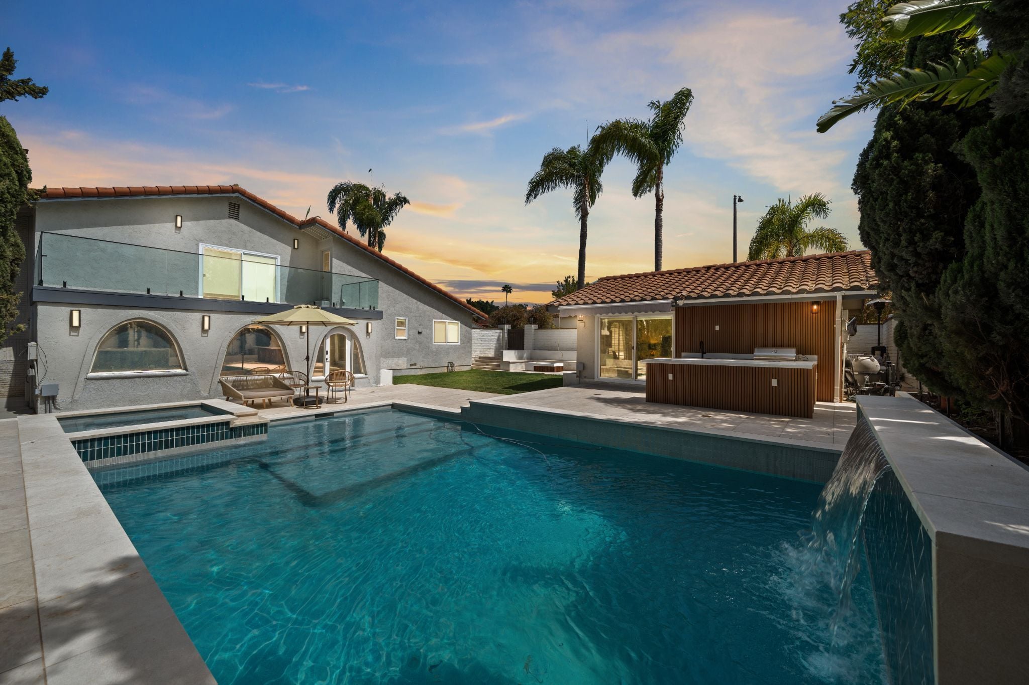 Luxury backyard pool with waterfall and sunset view